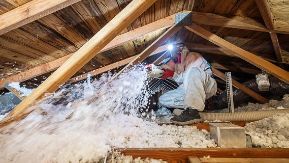 an attic space being filled with ceiling insulation