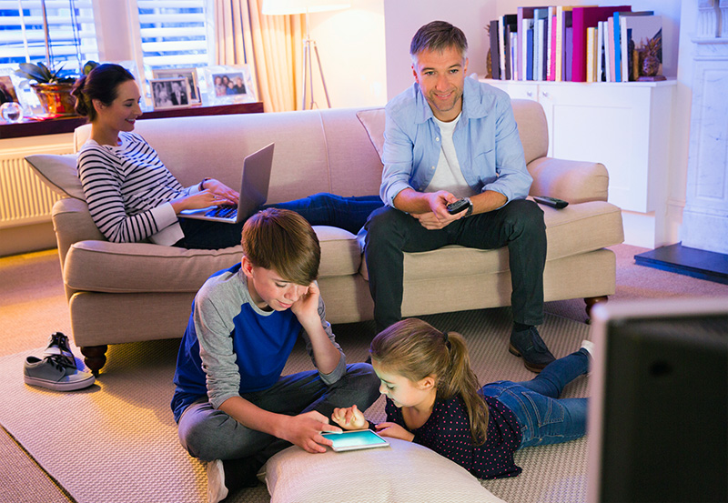 family on devices in living room