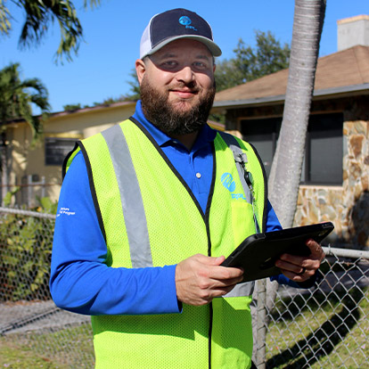 an fpl outreach specialist in a yellow safety vest holding a tablet