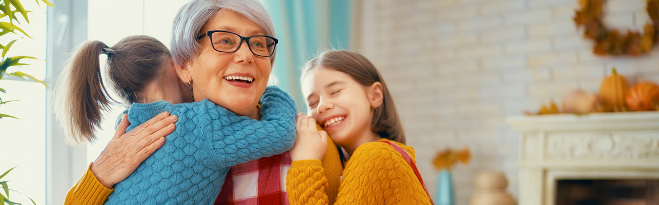 two granddaughters hugging their grandmother in the kitchen