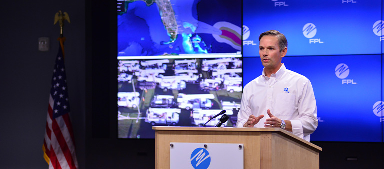 bryan garner standing at a podium in front of a grid of  screens addressing an audience