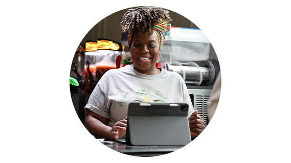 Round tile of a black business owner using a tablet in her juice shop
