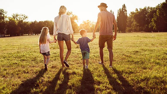 young family walking in a park with sunset