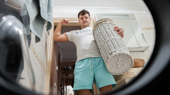man flexing his muscles in front of washer
